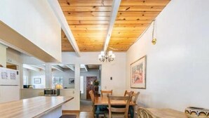 A modern kitchen with wooden ceiling beams, a dining area with a wooden table and chairs, and a refrigerator. - Beautiful Golf Course Views! (PE865-4) (Incline Village)