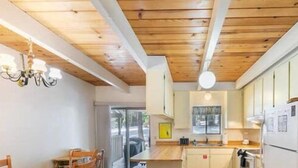 A modern kitchen with wooden beams, a dining area with a table and chairs, and a view through a glass door. - Beautiful Golf Course Views! (PE865-4) (Incline Village)