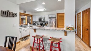 A kitchen with white cabinets, a granite countertop, and a wooden island with stools.