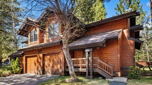 A two-story log cabin with a garage, a staircase, and a small porch.