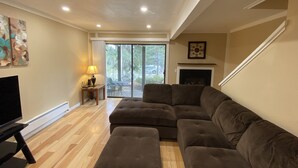 A living room with a sectional sofa, a flat-screen TV, a fireplace, and a sliding glass door leading to an outdoor area. - Cozy Condo in Incline (IM62) (Incline Village)