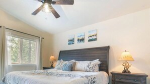 A bedroom with a bed, two bedside tables with lamps, a ceiling fan, and three landscape paintings on the wall. - Newly remodel and spacious home (830SO) (Incline Village)