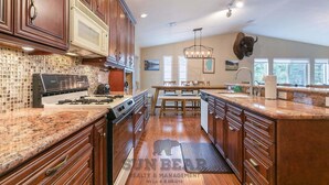 A kitchen with wooden cabinets, a gas stove, a microwave, and a large island with a sink. - Newly remodel and spacious home (830SO) (Incline Village)