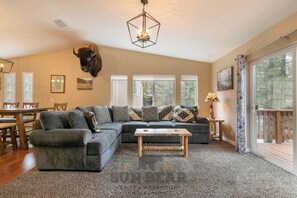A cozy living room with a sectional sofa, a wooden coffee table, and a bull head mounted on the wall.