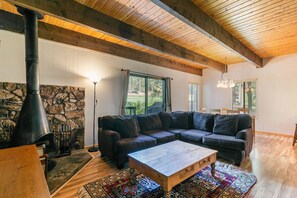 A cozy living room with a stone fireplace, a large sectional sofa, and a wooden coffee table.
