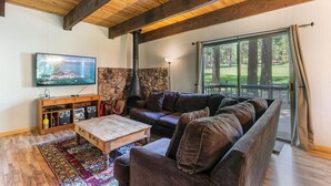 Een gezellige woonkamer met een stenen openhaard, een grote televisie en een houten salontafel.