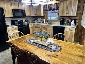 A kitchen with wooden cabinets, a microwave, a sink, and a dining table with chairs. - Bruno's Mountain Cave 3 Bedroom Cabin by RedAwning (Sevierville)