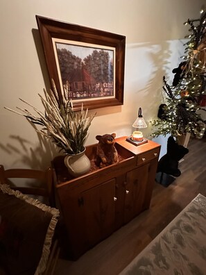 A wooden cabinet with a bear figurine, a potted plant, and a framed picture on the wall. - Bruno's Mountain Cave 3 Bedroom Cabin by RedAwning (Sevierville)
