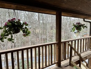 Ein hölzerner Balkon mit Geländer, der auf einen bewaldeten Bereich blickt.