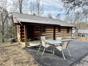 A rustic cabin with a porch, a table with chairs, and a stone wall. - Bruno's Mountain Cave 3 Bedroom Cabin by RedAwning (Sevierville)