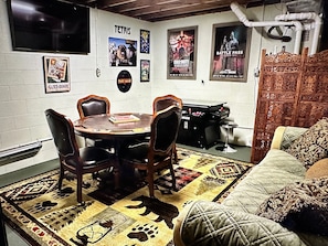 A room with a round table, four chairs, a sofa, and posters on the wall.