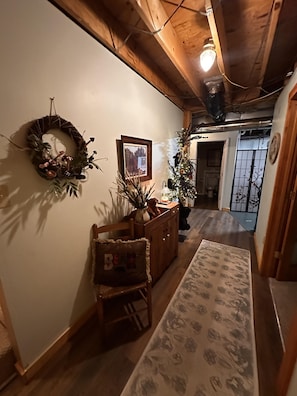 A hallway with a wooden ceiling, a wreath on the wall, a framed picture, a Christmas tree, and a patterned rug. - Bruno's Mountain Cave 3 Bedroom Cabin by RedAwning (Sevierville)