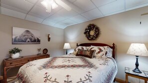 A bedroom with a large bed, a dresser, a nightstand, a wall-mounted lamp, a wall clock, a framed picture, and a decorative wreath. - Bruno's Mountain Cave 3 Bedroom Cabin by RedAwning (Sevierville)