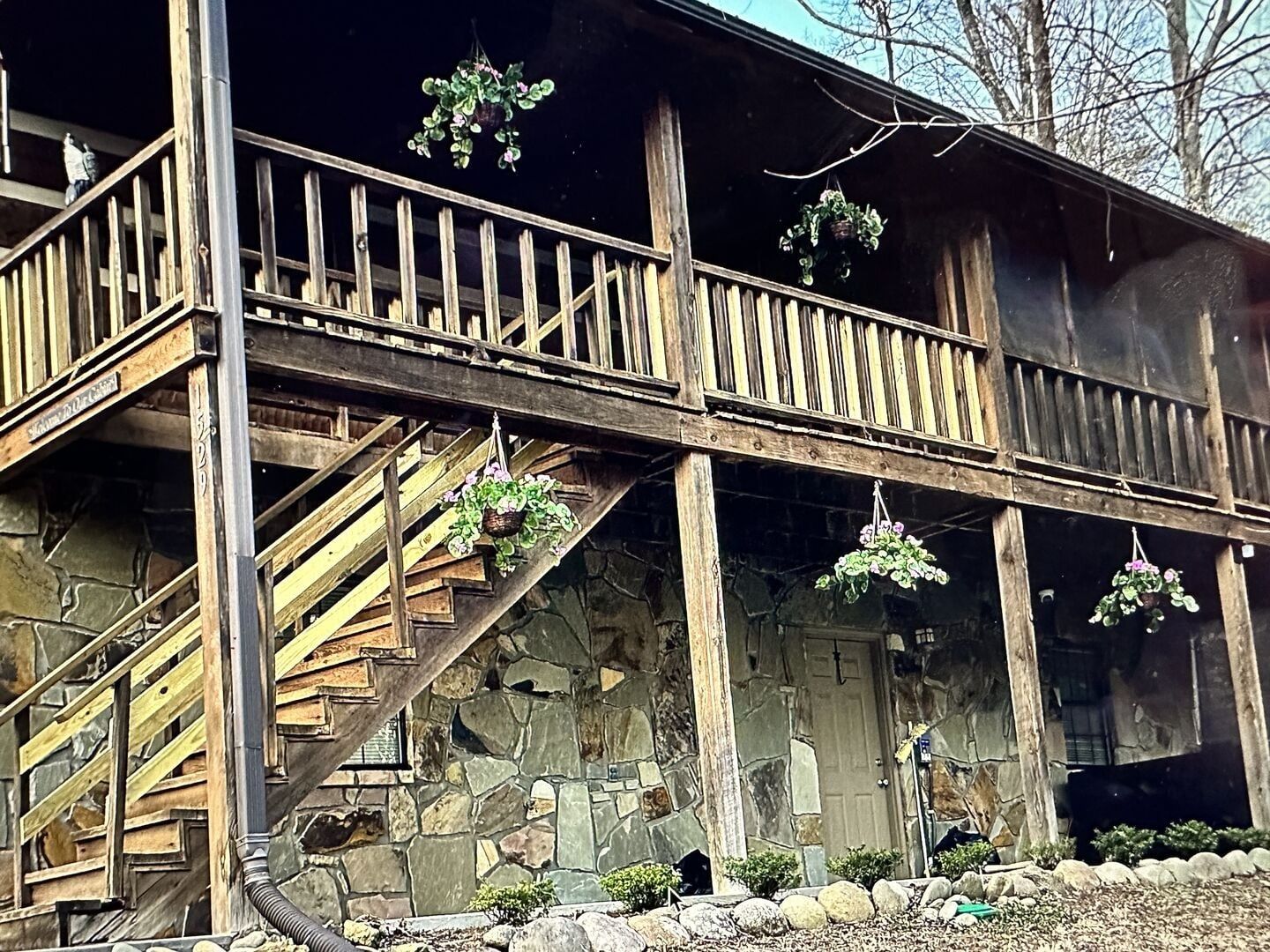 Eine Holztreppe führt zu einem Balkon mit hängenden Pflanzen.
