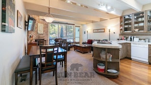 A spacious kitchen with a central island, a dining area with a brick wall, and a cozy living room with a fireplace. - Lakefront Condo Complex - Beach Access (LA999 35) (Incline Village)