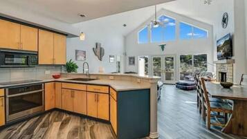 A spacious kitchen with a large island, wooden cabinets, and a modern ceiling light fixture.