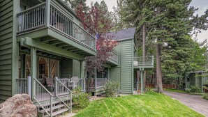 Ein zweistöckiges Haus mit Veranda, einer kleinen Terrasse und einem Vorgarten.