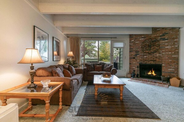 A living room with a fireplace, a sofa set, a coffee table, and a lamp.