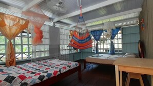 A room with two beds, a wooden table, and a ceiling fan. - Hostal Ebenezer Macedonia Tikuna (Leticia)
