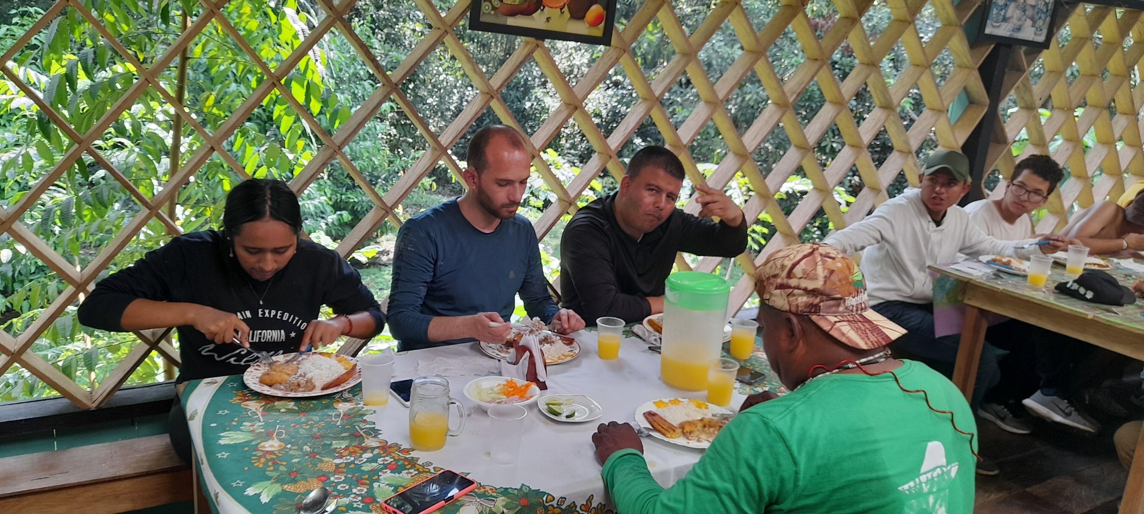 A group of people dining at an outdoor table with a lattice backdrop.