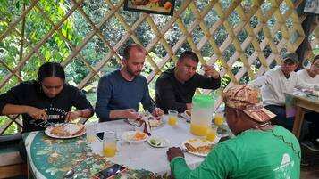 A group of people dining at an outdoor table with a lattice backdrop.