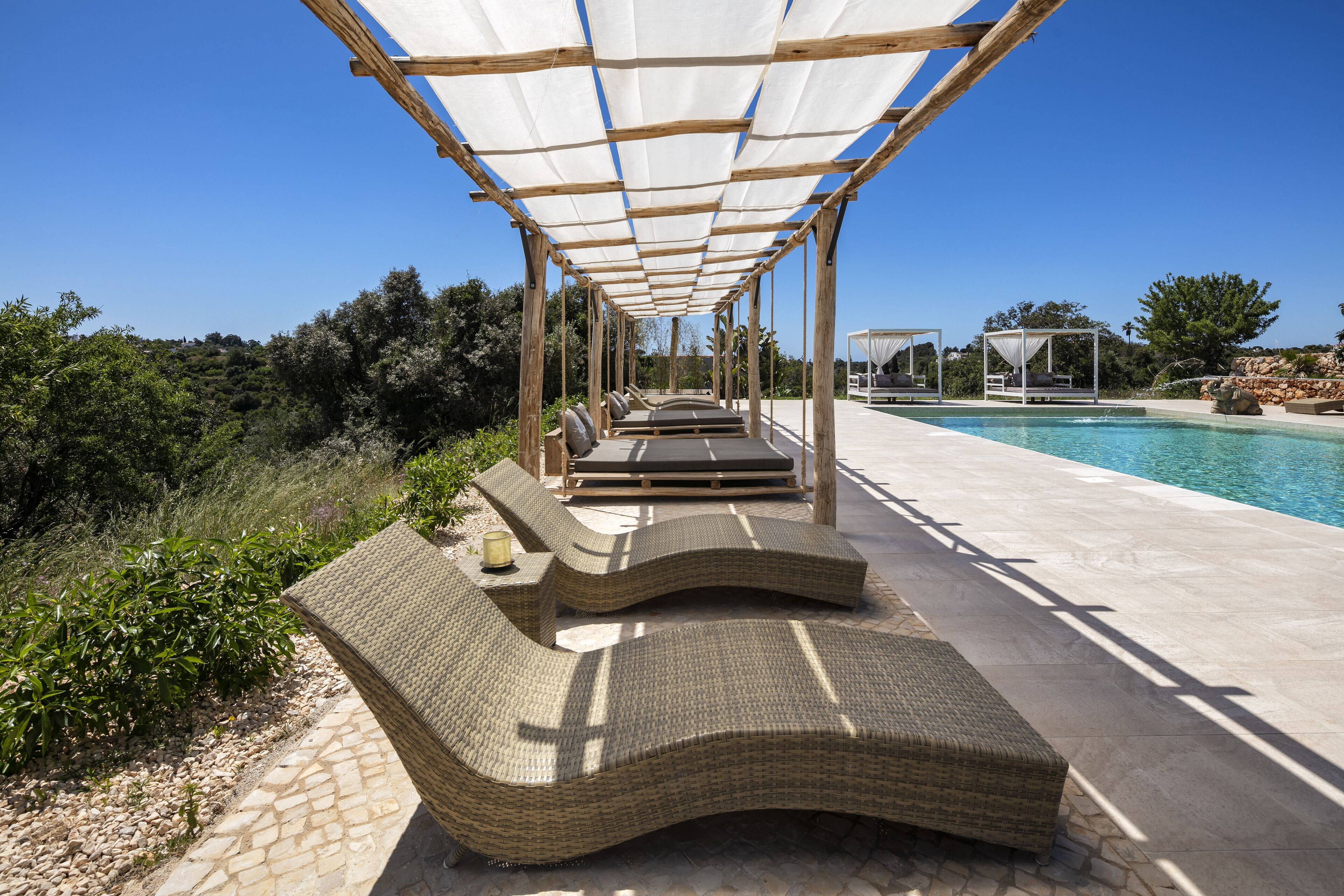 Un espacio de estar al aire libre cubierto con sillones de mimbre y una piscina.