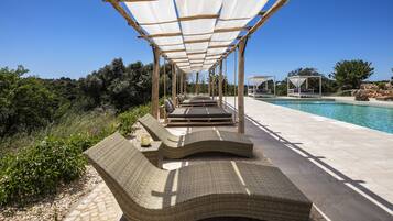 Un espacio de estar al aire libre cubierto con sillones de mimbre y una piscina.
