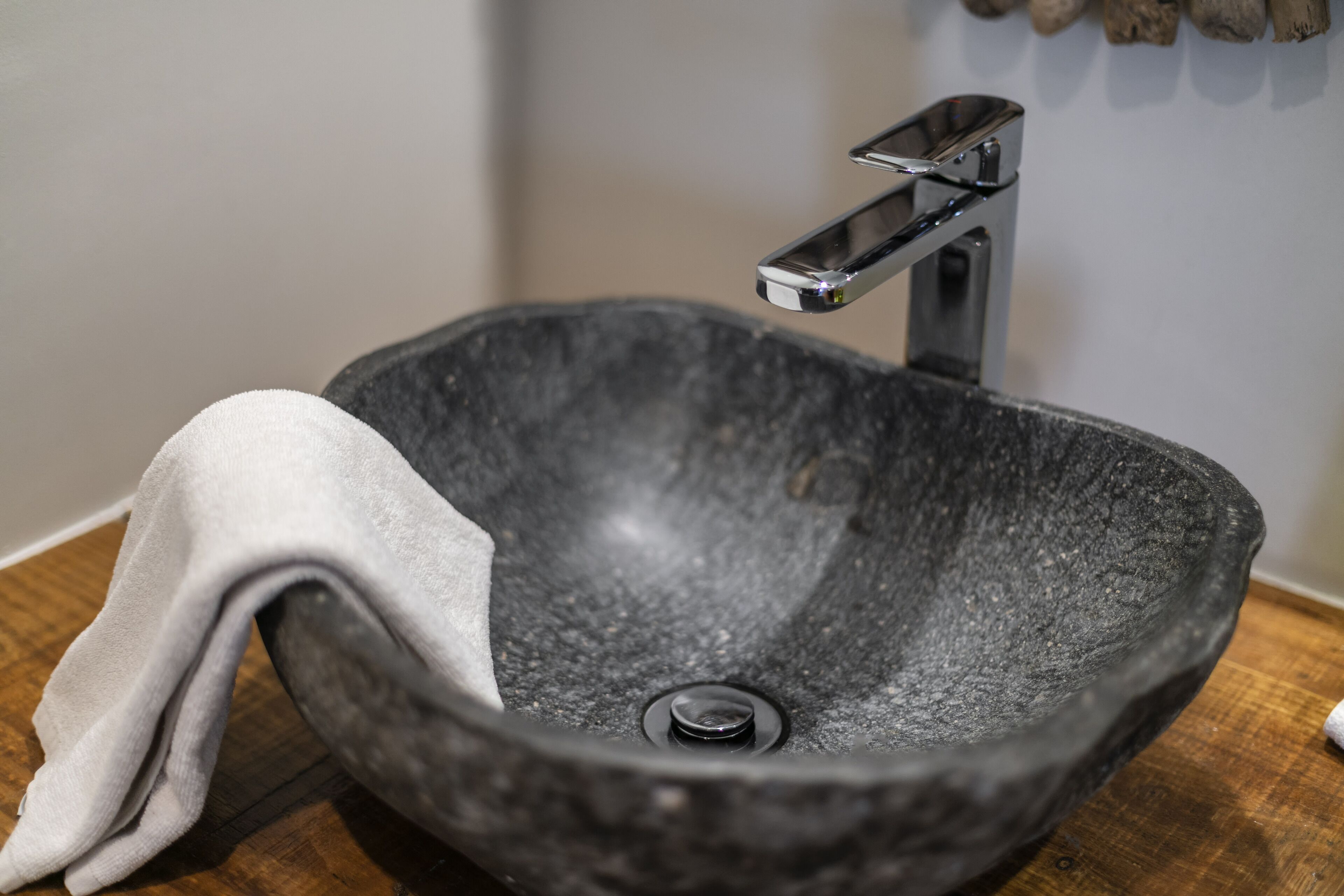A modern bathroom with a stone sink, a towel, and a wooden countertop.