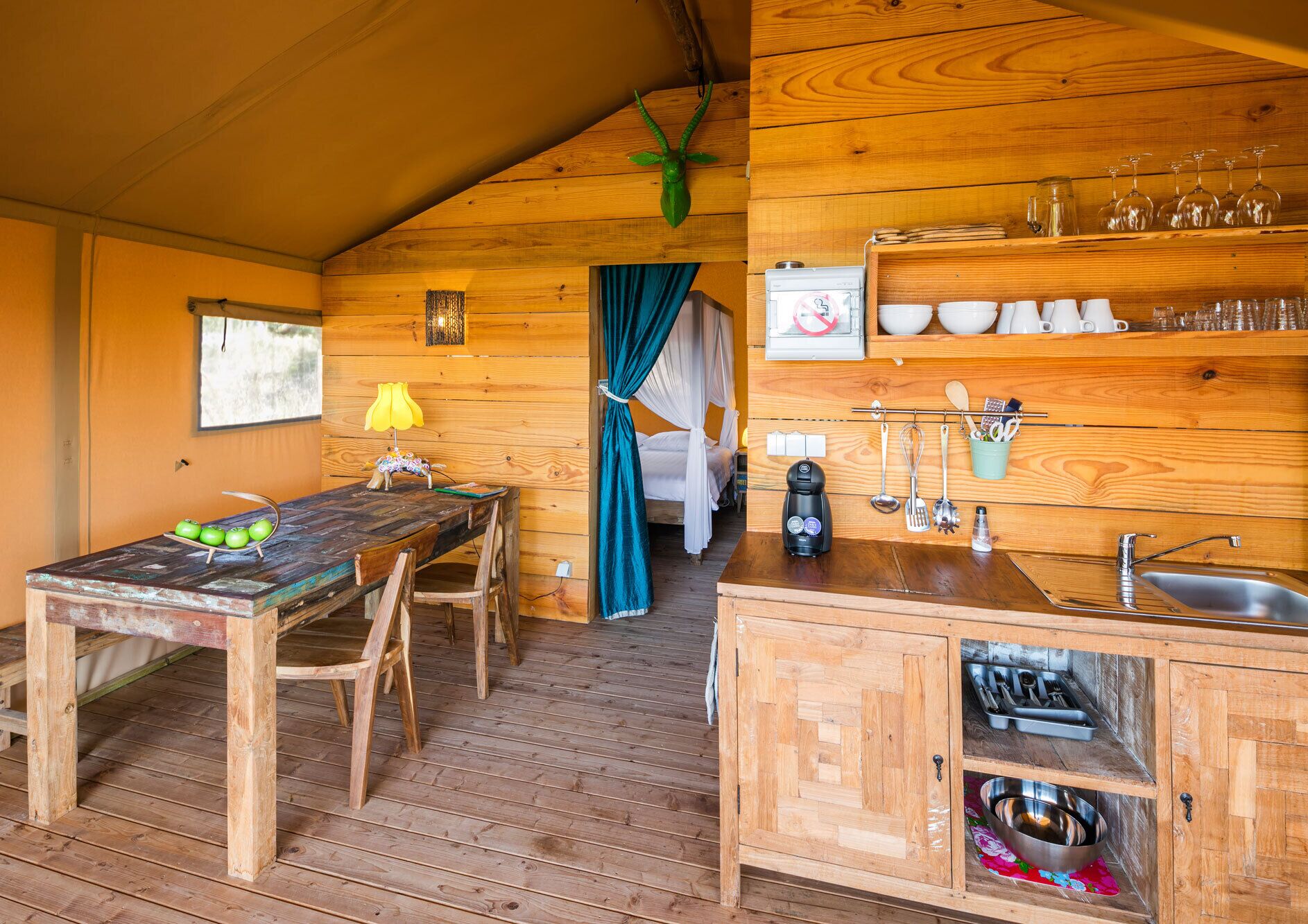 Een knus houten chalet met een eethoek, een keuken met basisvoorzieningen, en een slaapgedeelte met hemelbed.