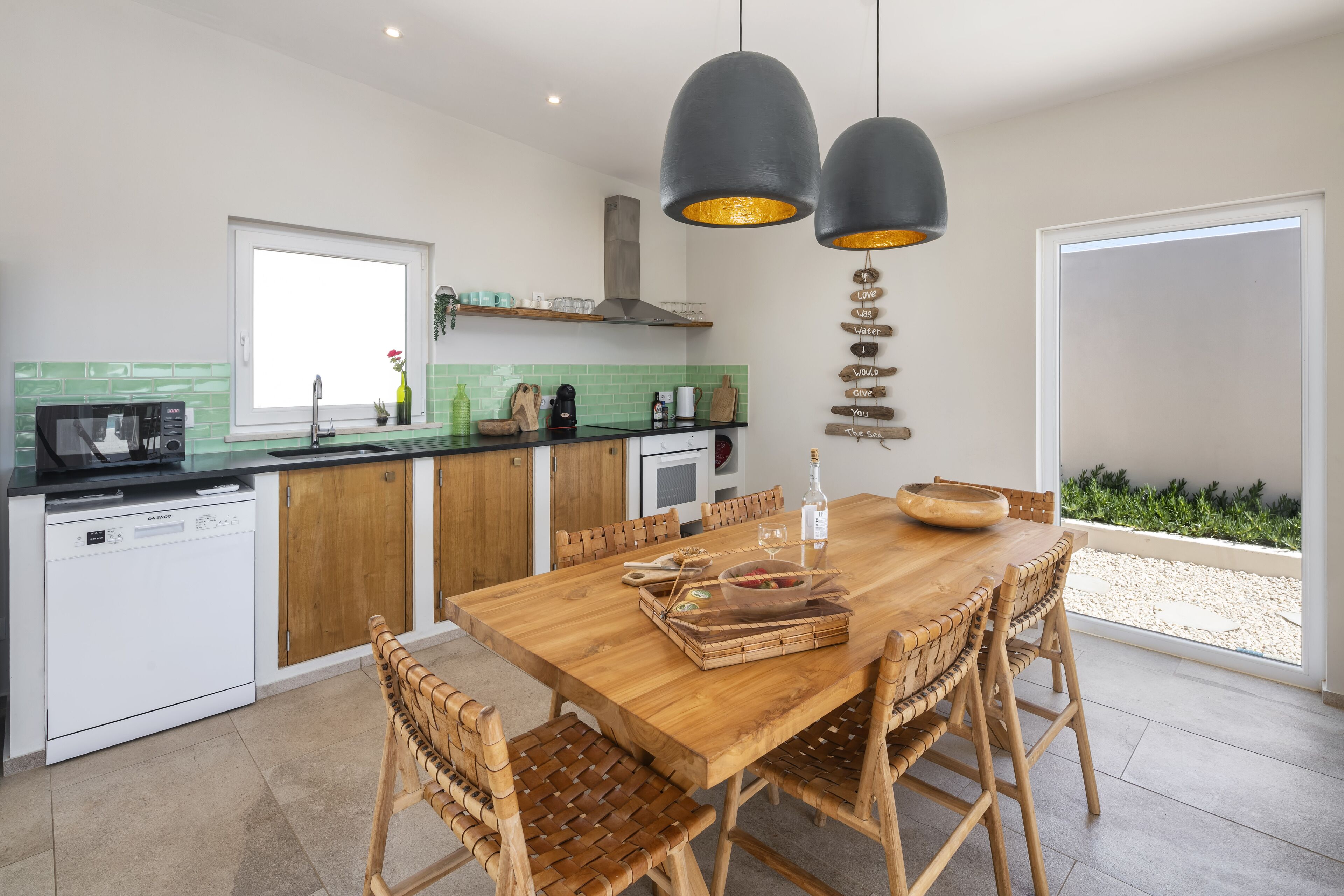 Eine moderne Küche mit Holztisch, Korbstühlen und Pendelleuchten.
