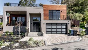 Et moderne hus med to etager, garage, veranda og anlagt indkørsel.