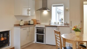 Una cucina moderna con mobili bianchi, piano cottura, forno e un'area pranzo con tavolo e sedie.