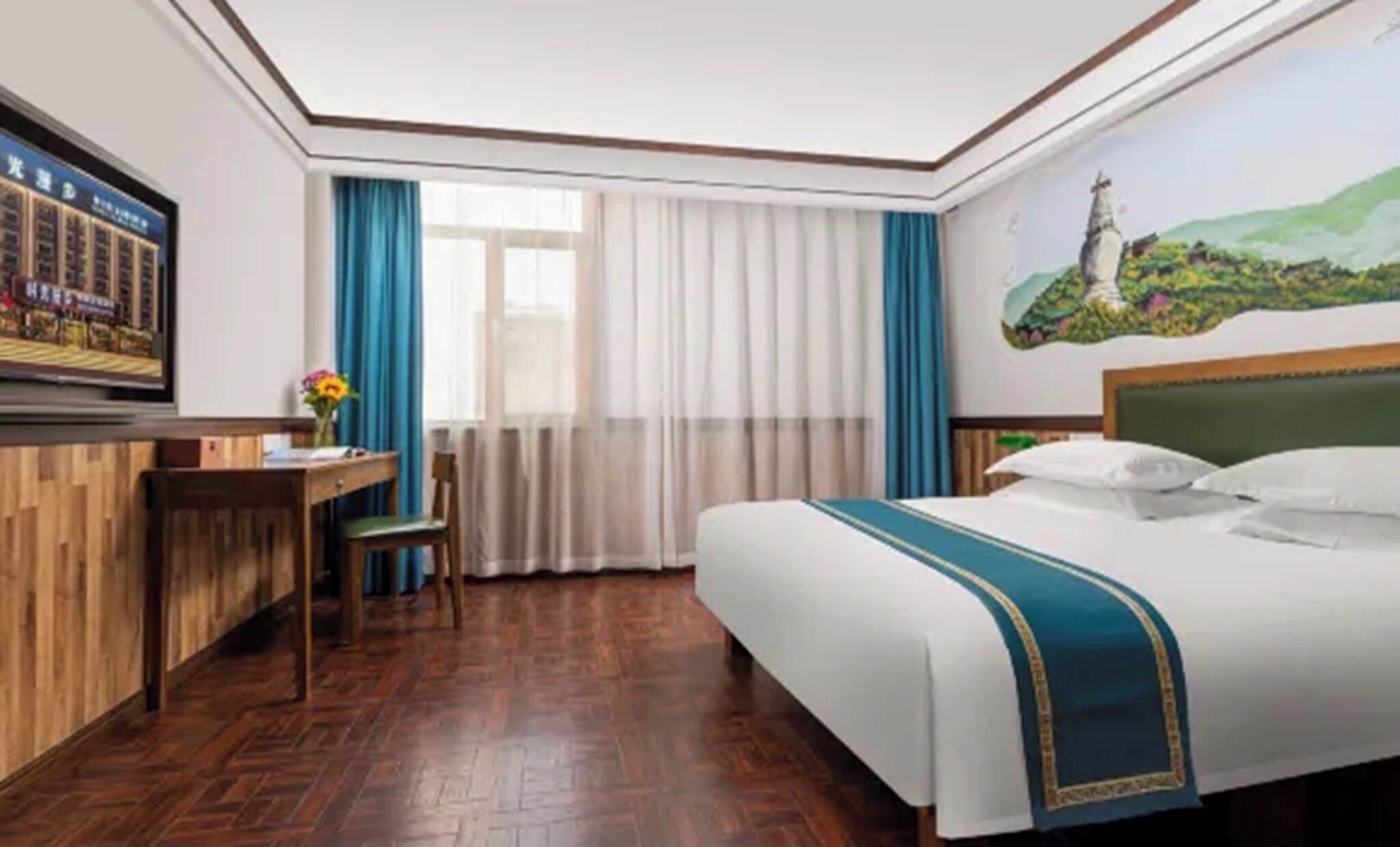 Ein Hotelzimmer mit einem Bett, einem Schreibtisch, einem Sessel, einem Fernseher und einem Bild an der Wand.