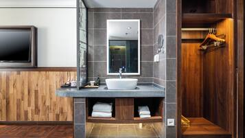 A modern bathroom with a wooden vanity, a large mirror, a built-in sink, and a shower area.