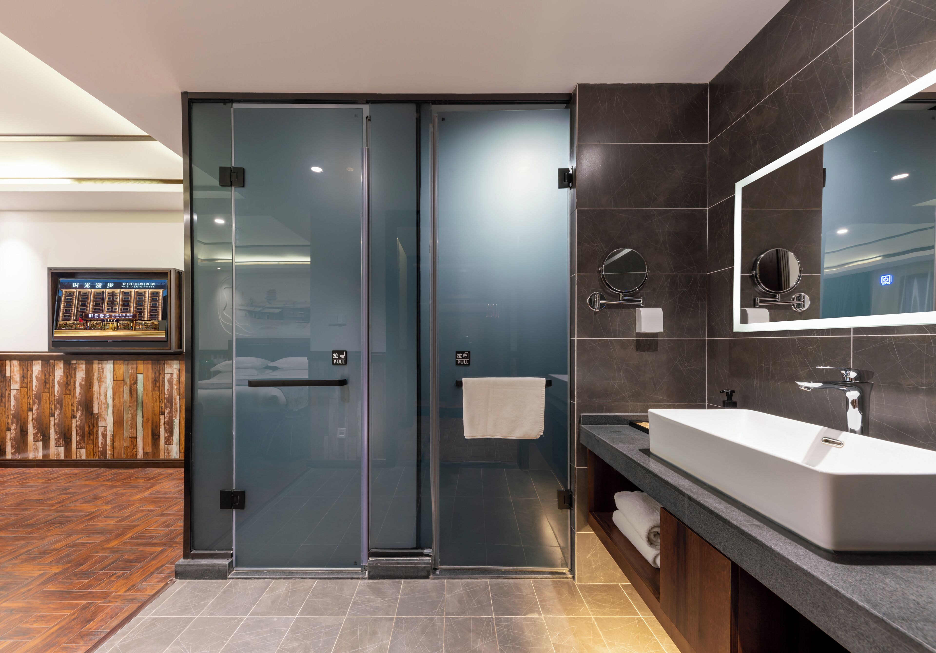 Un baño moderno con cabina de ducha de vidrio, un espejo grande y un mueble de tocador con lavabo.