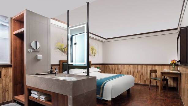 A modern hotel room with a wooden vanity, a large bed, a desk, and a view of the outdoors. - Nostalgia Hotel(Taiyuan Shanxi Museum) (Taiyuan)