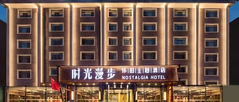 Un hotel con un letrero llamativo que dice 'Nostalgia Hotel' y caracteres chinos.