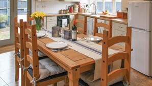 Eine Küche mit Holzmöbeln, einem Esstisch für zwei Personen und einem Kühlschrank.