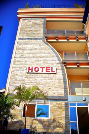 A hotel with a stone facade, a balcony on the upper floor, and a palm tree in the foreground. - Acactus Hotel kampala  (Kampala)