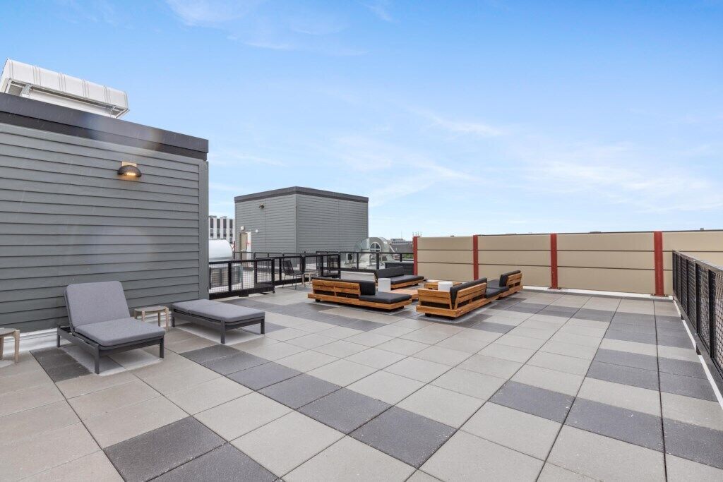 Una terraza en la azotea con zonas de estar, una parrilla y vistas del horizonte de la ciudad.