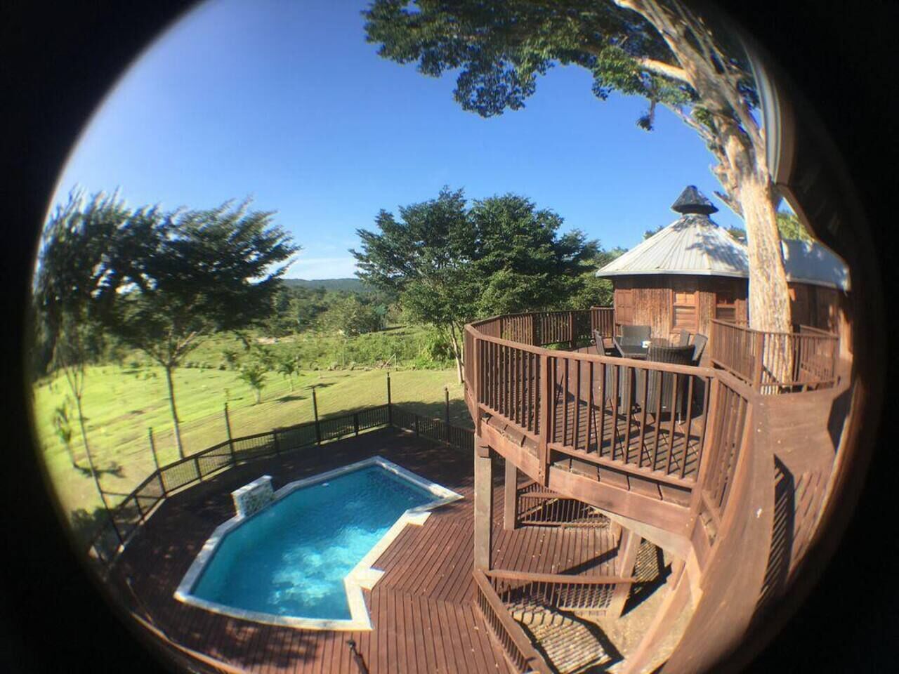 Ein Whirlpool auf einer Holzterrasse mit Blick auf eine Wiese und Bäume.