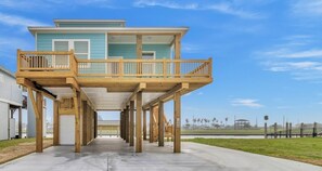 A two-story house with a wooden deck and a garage. - Fishermans Delight 3 Bedroom Home by RedAwning (Port Bolivar)