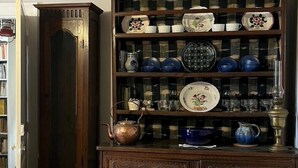 Un armadio in legno con ante in vetro che espone diversi piatti e utensili da cucina.