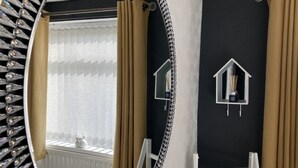 A bathroom with a large mirror, a radiator, and two wall-mounted light fixtures.