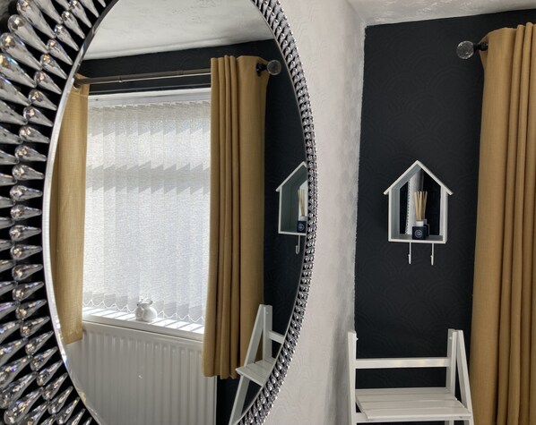 Un baño con un espejo grande, un radiador y dos luces fijadas a la pared.