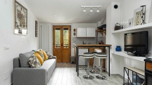 A modern kitchen with a central island, bar stools, and a TV on a stand.