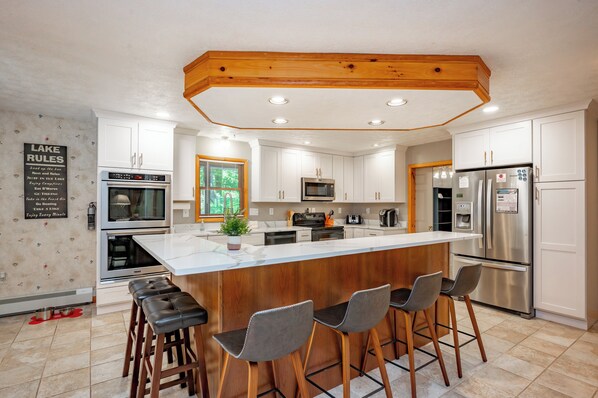 A modern kitchen with white cabinets, stainless steel appliances, and a wooden island with bar stools.
