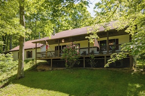 A two-story house with a porch, a flag, and a small garden.