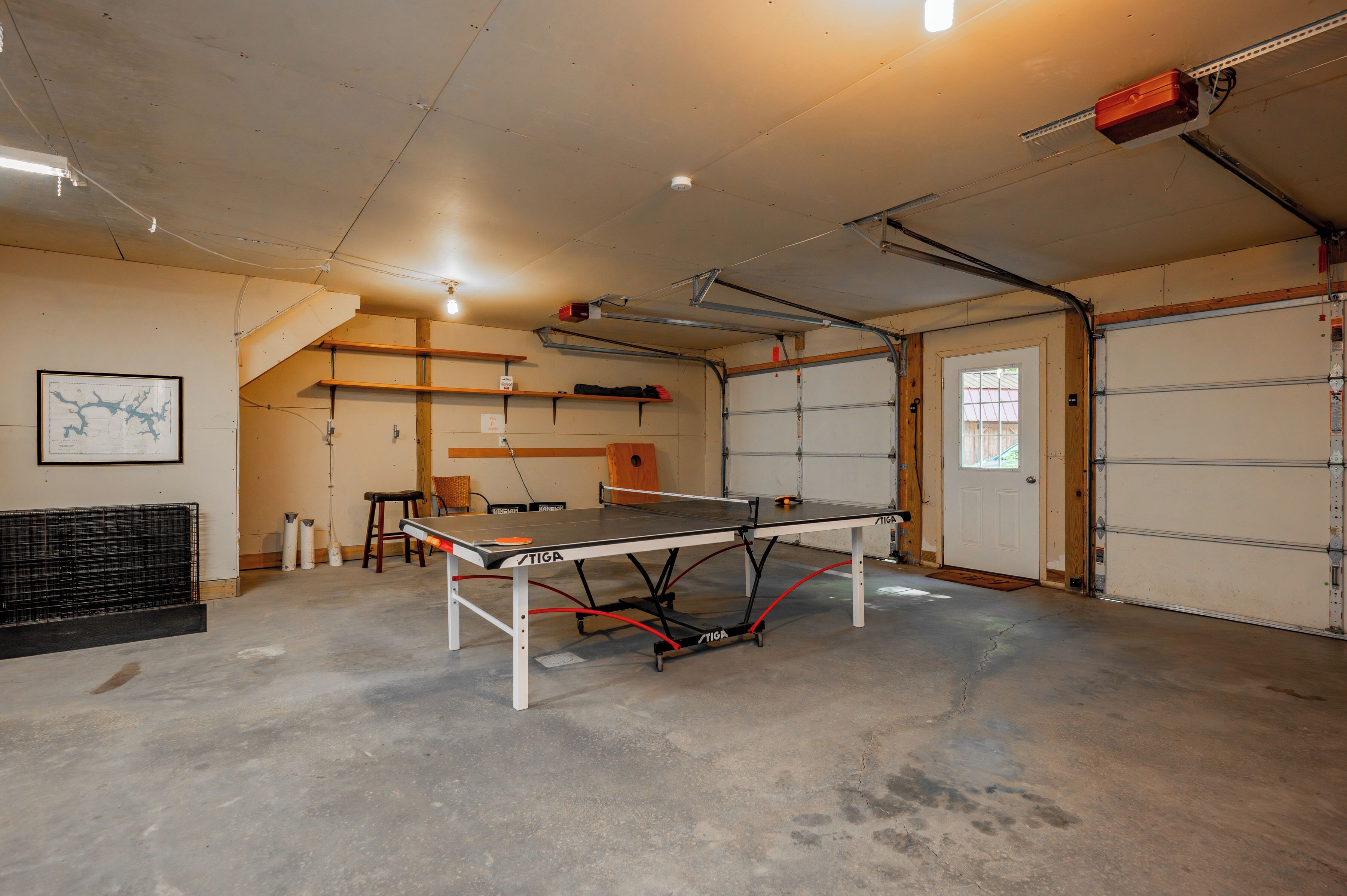 A spacious indoor area with a ping pong table, a radiator, and a door leading to a garage.