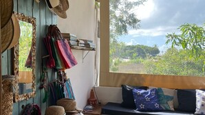 Una habitación acogedora con un banco de madera, un sofá con cojines y un ventanal con vistas al verdor.
